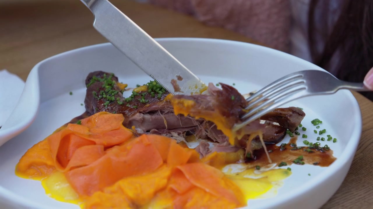 Eleganckie danie restauracyjne z pieczoną kaczą nogą, puree marchewkowym i bogatym sosem, podane na nowoczesnym talerzu.