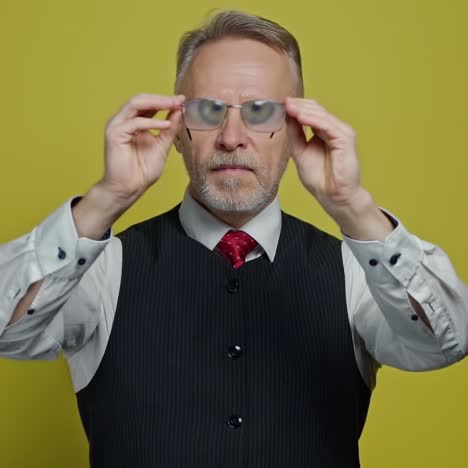 funny big eyes of an old man through glasses. mature man holding eyeglasses in front of his face. positive emotions.