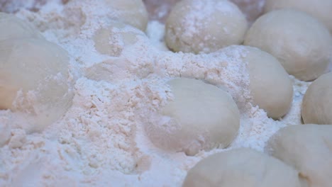 close up of dough balls on a table, covered in flour