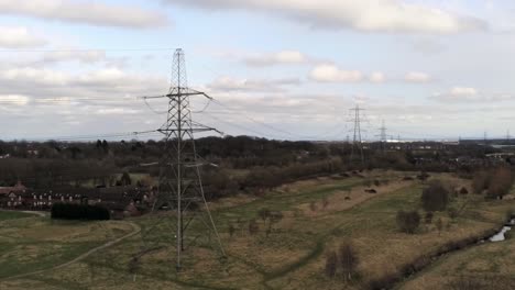 electricity distribution power pylon overlooking british parkland countryside, aerial view pull back shot