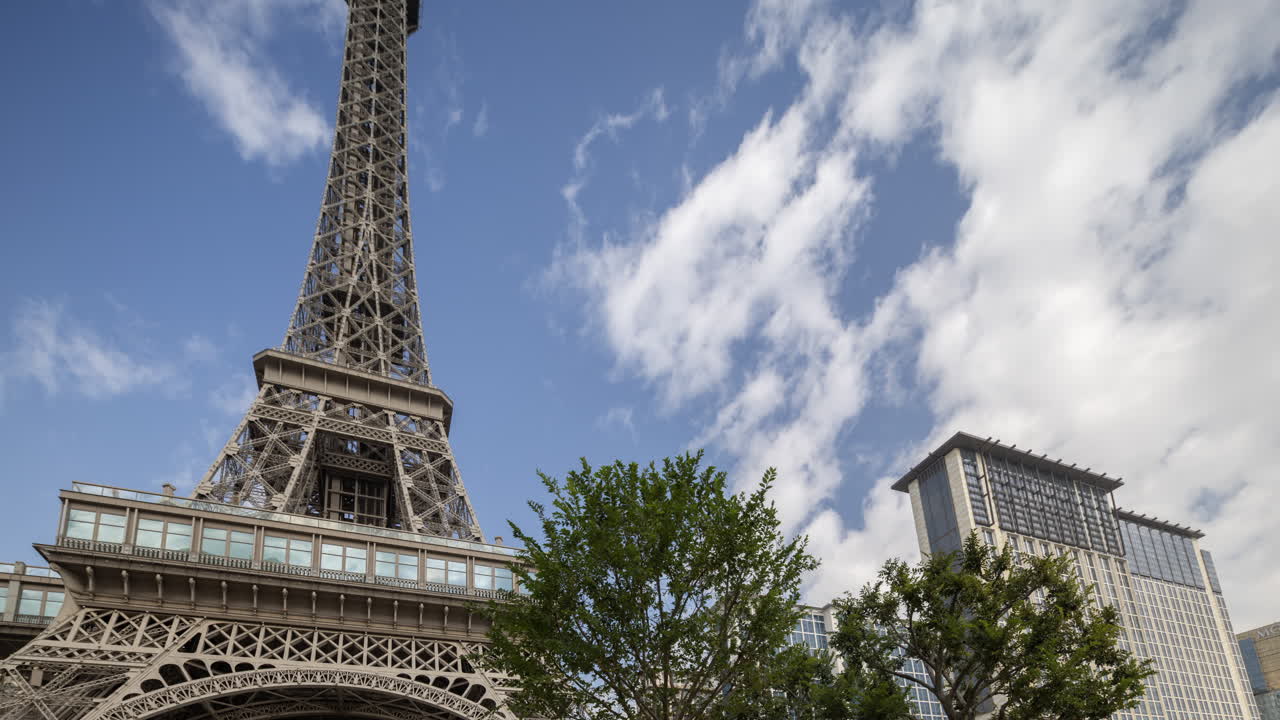 Time-lapse di una replica della Torre Eiffel e di un edificio moderno con nuvole in movimento