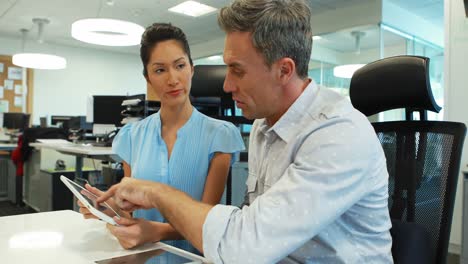 business colleagues discussing over digital tablet at desk