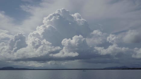 enormes nubes de tormenta se asoman detrás de una canoa que se mueve en la distancia a través del lago guatemala