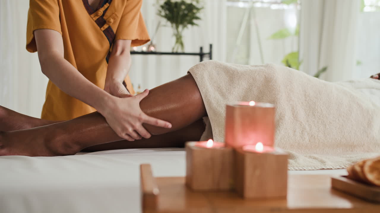 Donna anonima che esegue un massaggio alle gambe di una cliente in un centro benessere
