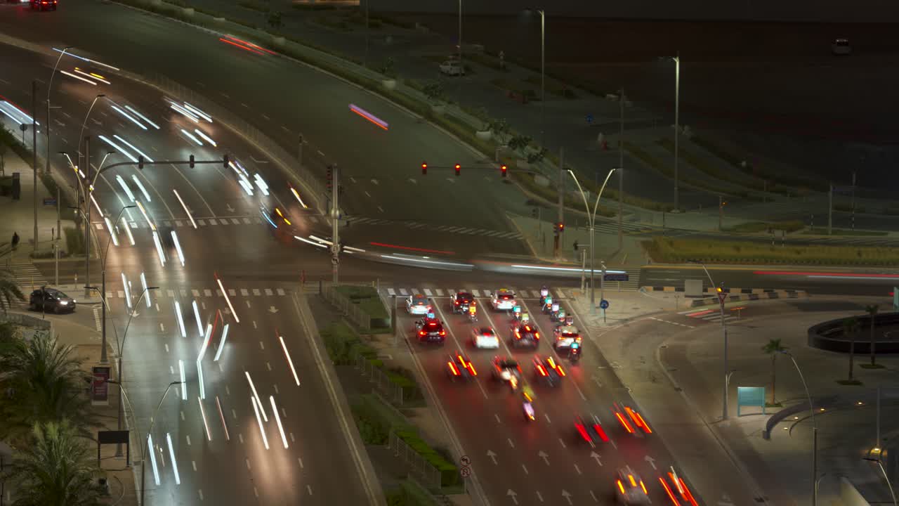 Busy city vehicular traffic intersection, crossroads, or junction in Abu Dhabi, United Arab Emirates - nighttime time lapse with smooth motion blur