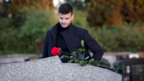 young man at the cemetary with a flower