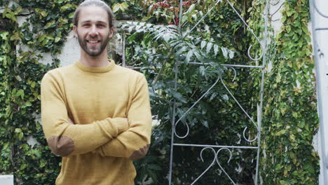 retrato de un hombre caucásico con un suéter amarillo cruzando los brazos en el jardín, cámara lenta, copia del espacio
