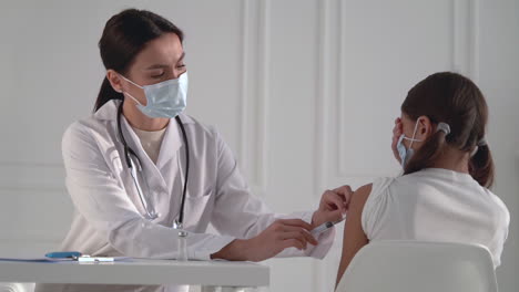 Female-nurse-administering-a-Coronavirus-vaccine-to-a-girl.-Doctor-giving-an-injection-for-the-Covid-19.