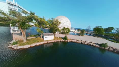 FPV-drone-video-of-geodesic-sphere-dome-building-beside-marina-on-Lake-Ontario-at-Ontario-Place-in-Toronto-Canada