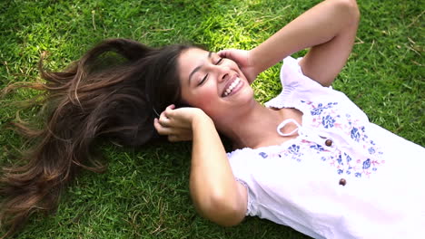 pretty girl lying on the grass listening to music