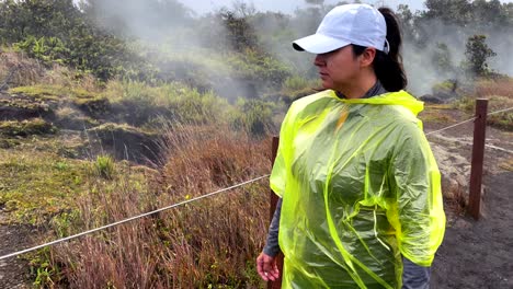 hispanic woman walking on the outside rim of mauna loa volcano in hawaii, sulfur vapors smoking grounds