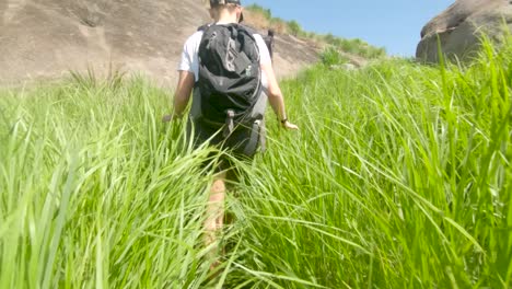 A-down-low-slow-motion-tracking-shot-of-a-blonde-western-woman-pushing-through-thick-and-long-grass-while-trekking-in-East-Africa