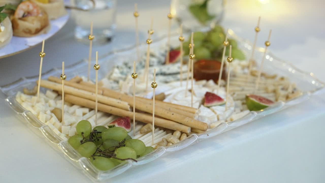 A beautifully arranged cheese platter features a variety of cheeses, grapes, and snacks served for a small gathering. Guests enjoy the tasty selections while socializing