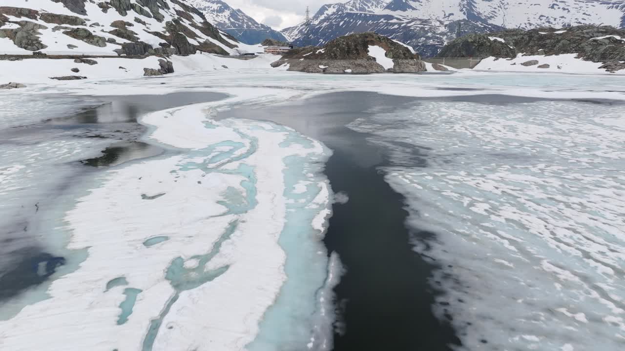 Tilt-up reveal view of Totensee or Totesee iced lake and dam at Grimsel Pass in Switzerland