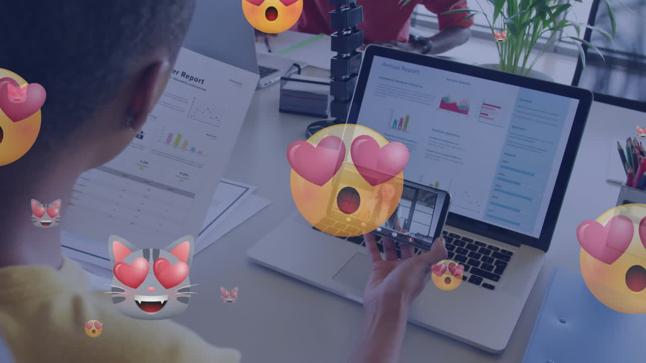 animación de ojos de corazón cara emojis sobre mujer afroamericana teniendo llamada de video en teléfono inteligente