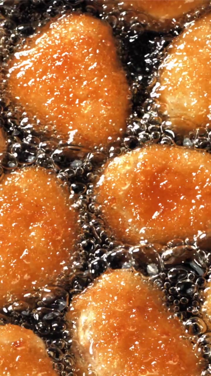 Cibo dorato che frigge in olio caldo e ribollente