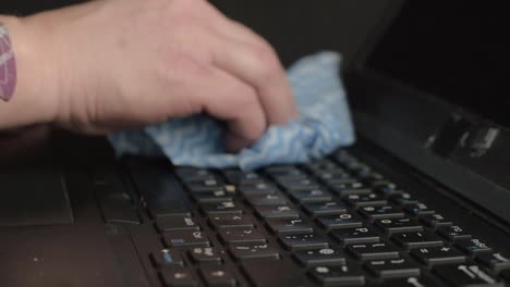 manos y dedos limpiando el teclado del portátil con un primer plano de tela.