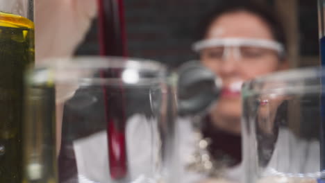 woman with magnifier glass shakes test tube with red liquid