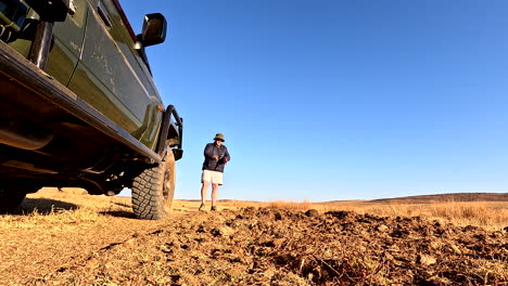 low pov next to safari truck as field guide explains spoor tracking to tourists