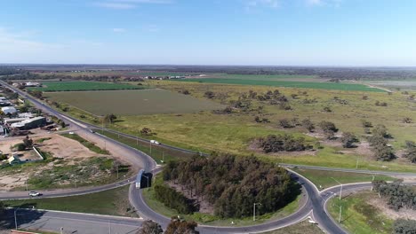 trucks and cars driving on the road through green fields, sunny day with blue sky, aerial shot