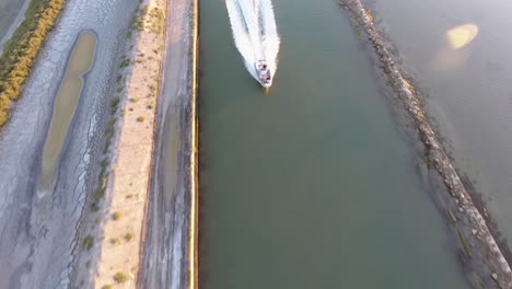 following a boat in a canal during sunset. discovering the horizon and the sea