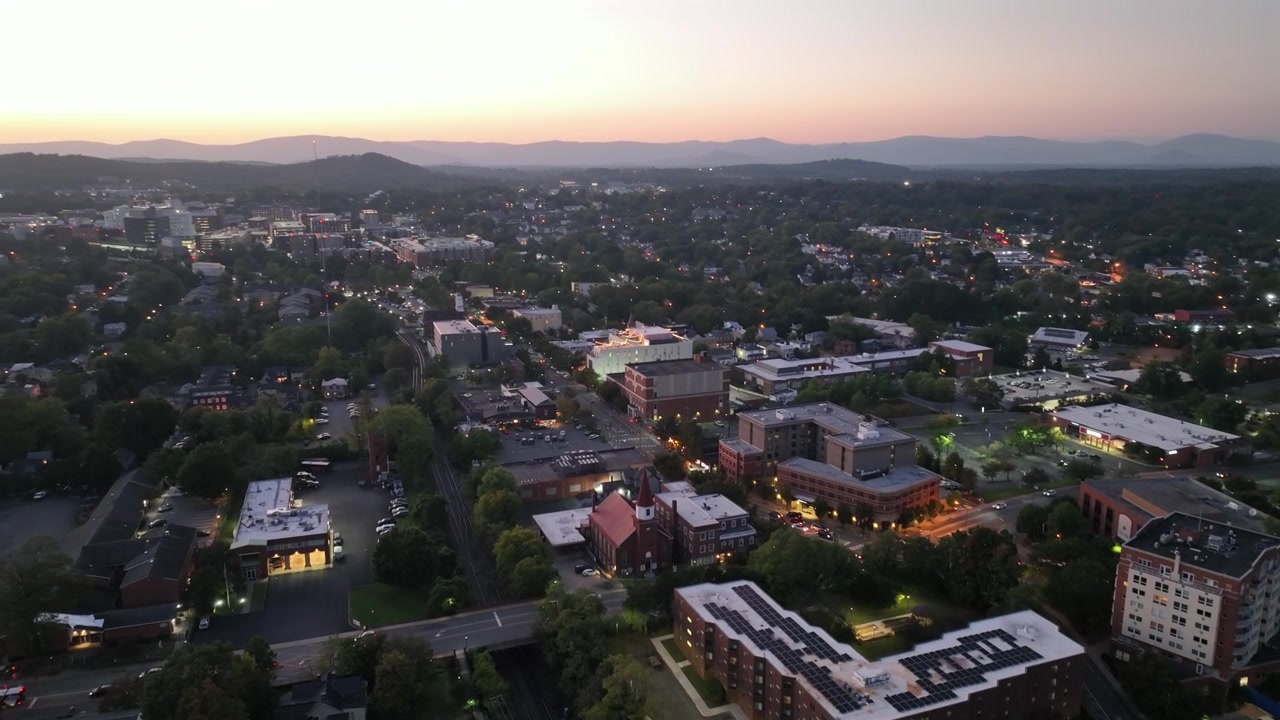 Veduta aerea di una città americana con traffico sulla strada principale al crepuscolo. Città storica in Virginia con pannelli solari sull'edificio. Lanterna illuminata e area residenziale nel centro. Campo lungo