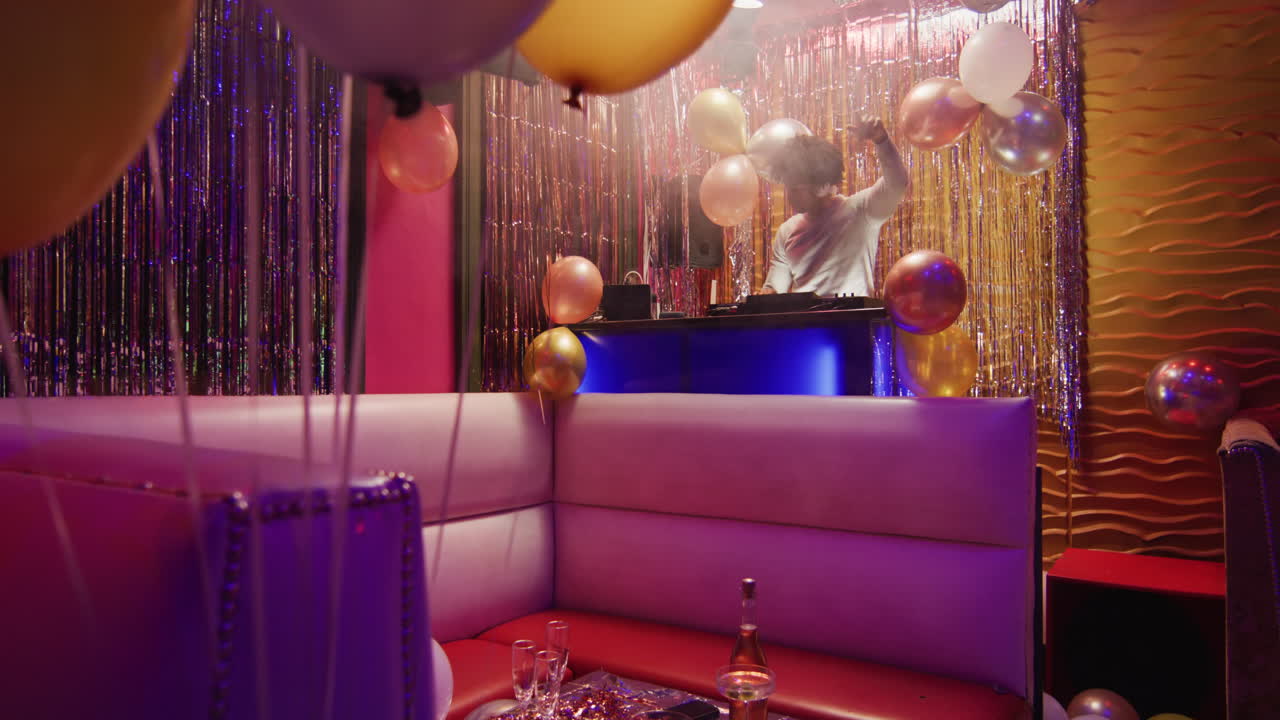 Video of happy african american male dj playing music, dancing and using microphone at a nightclub