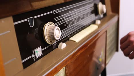 close-up of man's hand rotating the knob on the old radio. concept. vintage technology