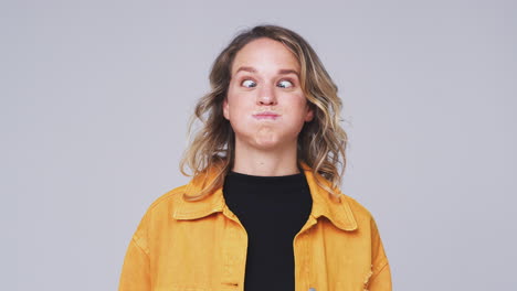Head And Shoulders Studio Shot Of Woman Pulling Faces And Smiling At Camera In Slow Motion
