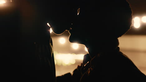 young african american couple kissing in rain holding hands enjoying romantic connection on beautiful rooftop at night