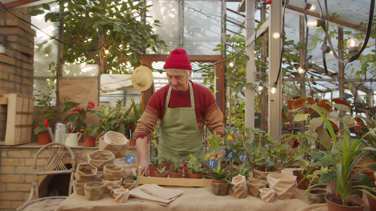 hombre mayor etiquetando plantas en el vivero de flores