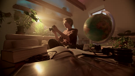 man with vintage camera and globe in a cozy, plant-filled room