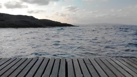 The-shot-is-moving-horizontally-along-wood-pier-from-the-shore-to-the-sea-in-sunset