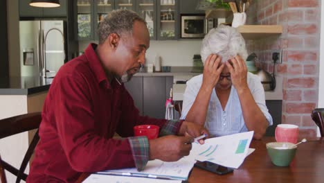 Senior-African-American-husband-and-mixed-race-wife-working-together-at-home