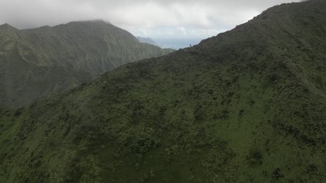 aerial: tourist silhouette on ridge top trail in hawaii mountain fog