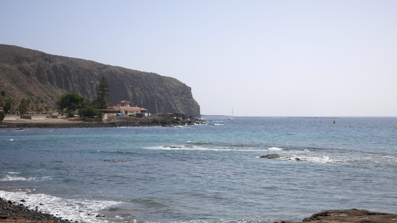 Coastal tranquility meets rugged cliffs, a luxury villa of wealthy retreat perched by the sea, with waves gently reaching the shoreline