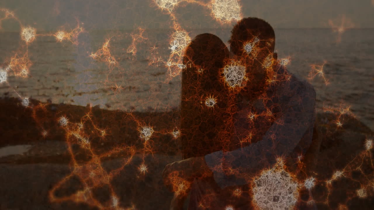Embracing on beach, couple with glowing fractal animation overlay at sunset