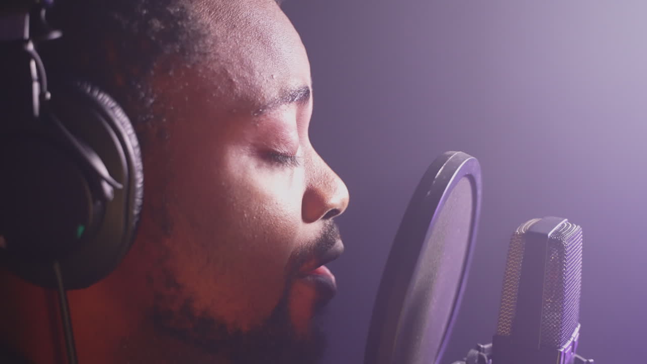 hombre cantando en un micrófono en un estudio de grabación