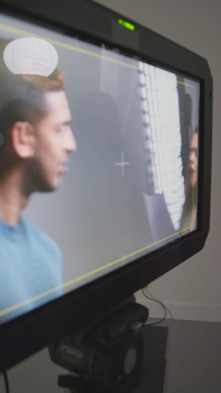 video vertical de una directora de cine y actores viendo ensayos de rodaje de una película o video en un estudio en un monitor