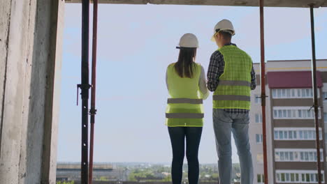 building workers working at construction site builders looking in blueprint back view copy space. building development teamwork and people concept.