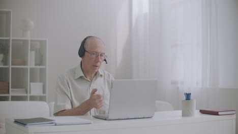 aged male boss is talking with employees by video call giving orders communicating online with office