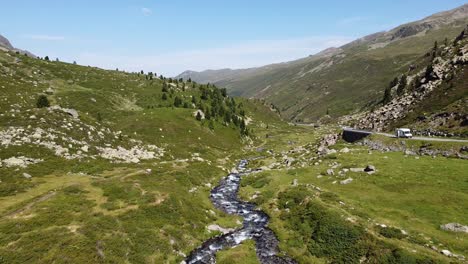 Schweizer-Nationalpark---Luftdrohnenansicht-Des-Grünen-Bergtals,-Des-Strömenden-Flusses-Und-Der-Malerischen-Straße