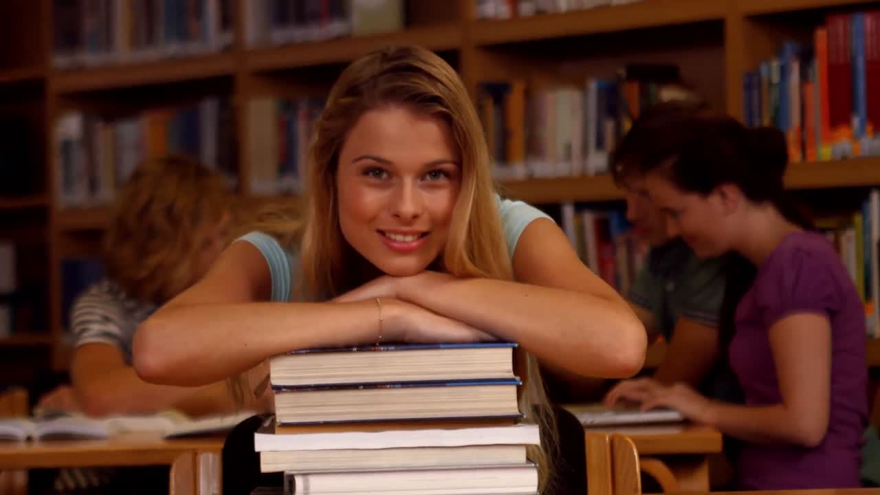 estudiante sonriendo a la cámara en la biblioteca