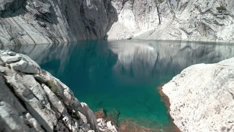 person going to a remote blue lagoon with granite big walls on the surroundings