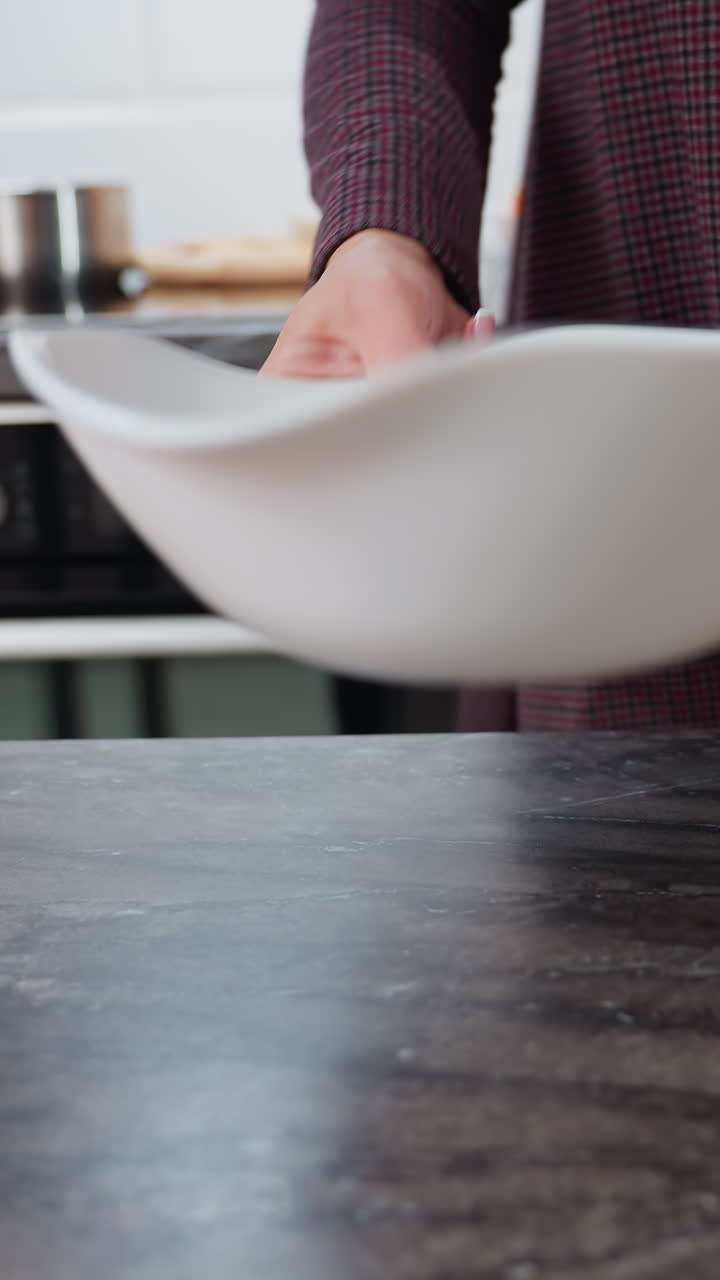 vista parcial de la mujer girando sosteniendo un cuenco blanco, colocándolo suavemente sobre la mesa, deja caer cuidadosamente huevos en el mostrador con su mano adornada con una pulsera