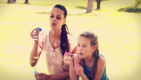 madre e hija soplando burbujas