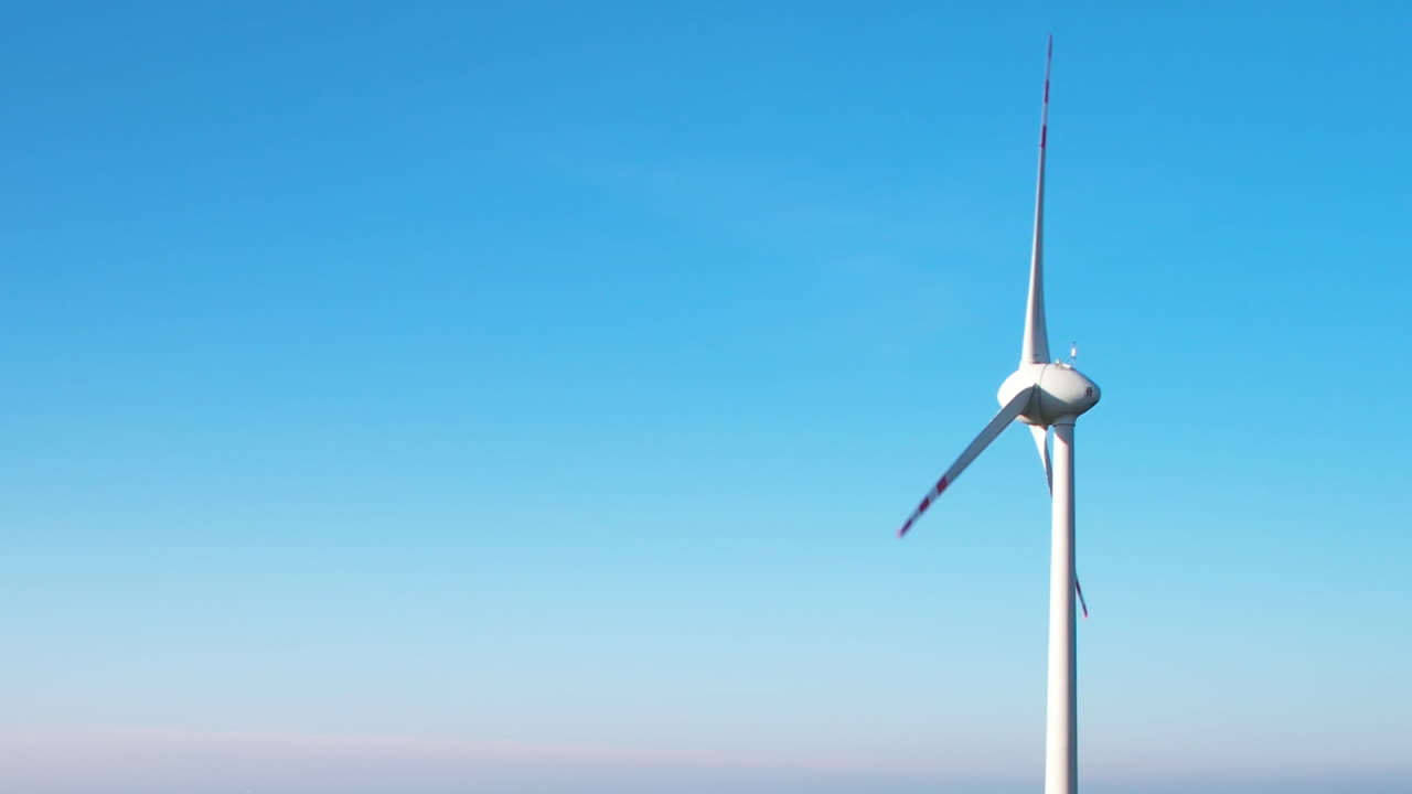 ⁇ 은 파란 하늘을 배경으로 회전하는 블레이드와 함께 단일 거대한 풍력 터빈을 바로 지나