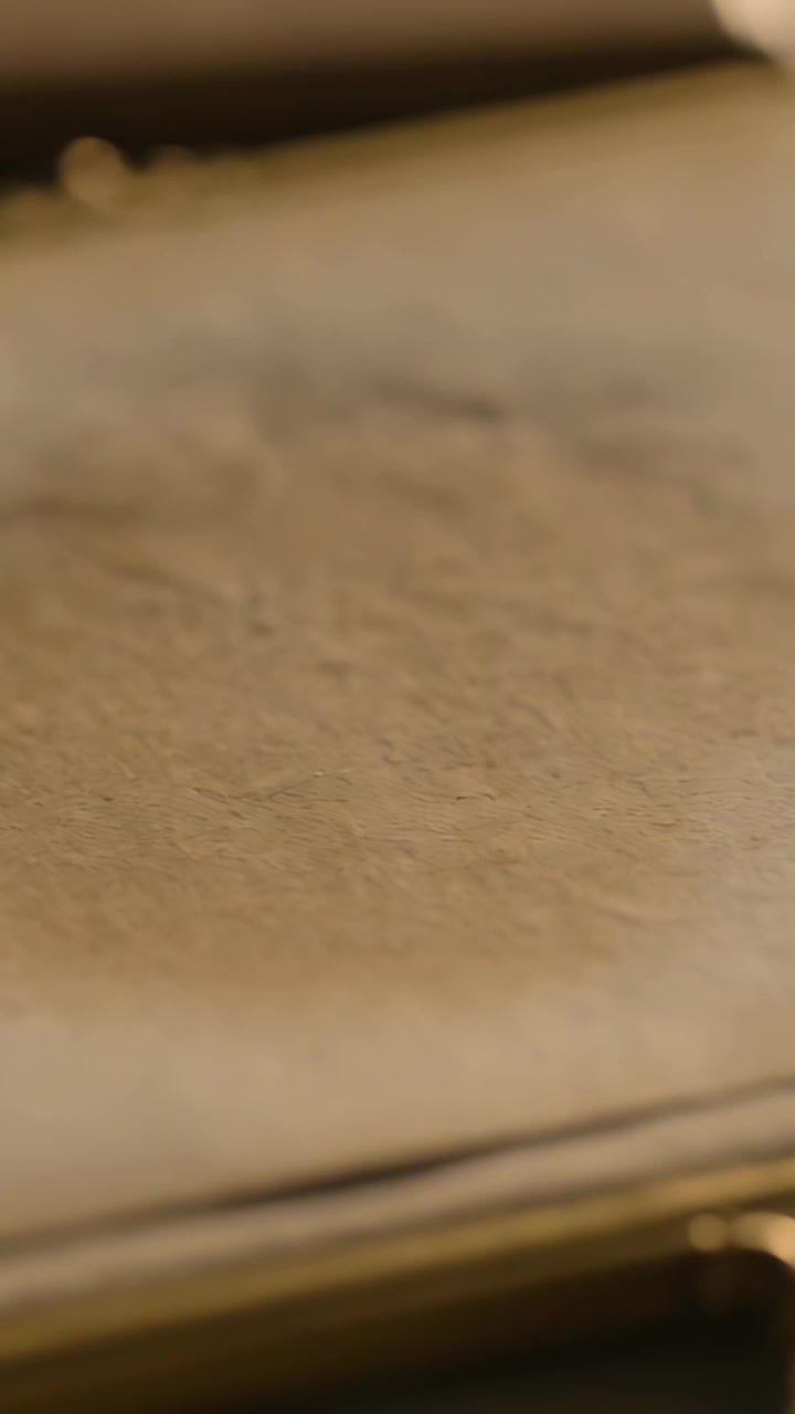 Video verticale: La telecamera si sposta mostrando una superficie granulosa beige in macro, evidenziando il bordo e la trama.