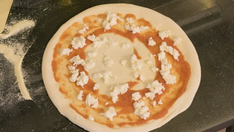 top view of an unrecognizable chef adding cheese on the pizza raw dough