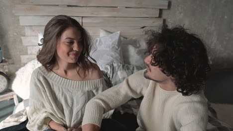 young romantic playful couple sitting in bed wearing winter clothes